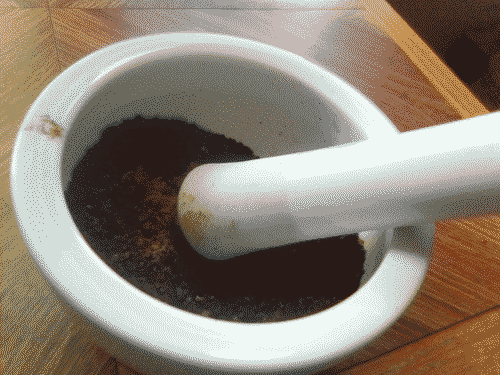 Ground beans with cinnamon in mortar with pestle