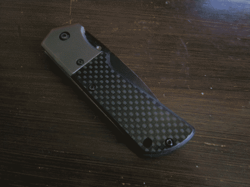 Trusty knife folded up - carbon fiber weave and grey handle with black anodized blade visible along the edge