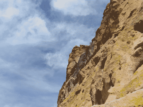 Stark sandstone cliff against a beautiful blue and white mottled sky