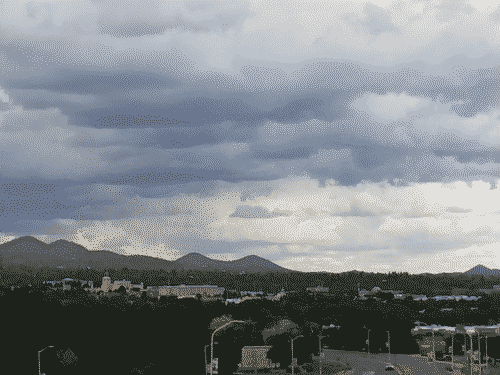 View across Santa Fe to the east showing dark clouds hanging ominously above the mountains.