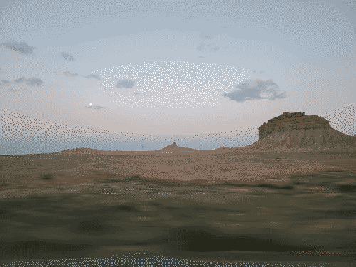 Unknown rock formation across the desert with the moon visible against the colors of the sunrise