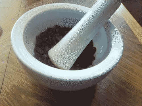 Whole coffee beans in mortar with pestle