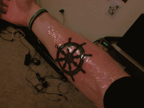 Dharma wheel tattoo on inner right forearm about one hour after completion with transparent saniderm film on it
