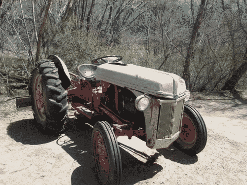 Oldschool tractor resting in a dirt driveway