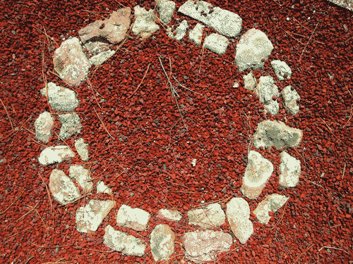 White stones forming a ring amid smaller red pumice