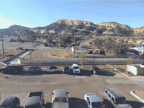 View of Gallup looking out the window at the end of the 3rd floor cooridor in a hotel; beyond the parking lot is a wonderful rocky hill characteristic of the region