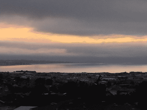 Sunset across the monterey bay from Seaside, looking towards Monterey/Carmel. Fog hangs over the carmel hills and bleeds into the bay.