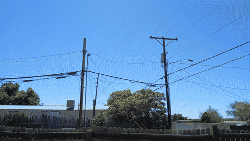 a view over the roof of a modular home; two power poles are in front of the building