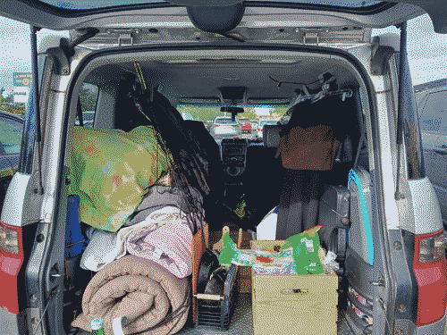 View from behind with the hatchback and tailgate open - the bed, kitchen, and pantry modules are immediately visible from left to right and the stuff hanging from the rear handholds are dark in the background